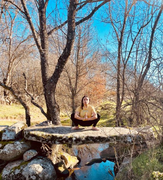 Briguitte Salgado sentada en una roca junto a un arroyo, en un bosque.